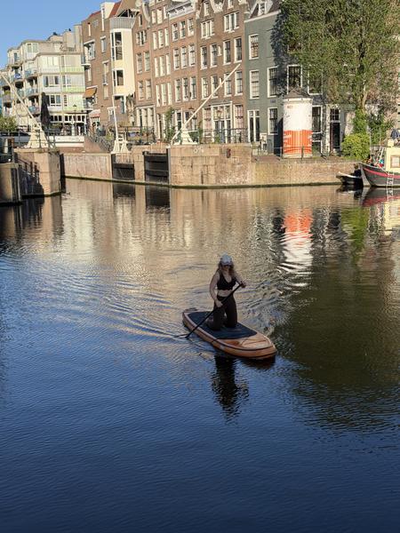 A person is gracefully paddleboarding on the calm waters of the canal in Oudeschans, Uilenburg, Amsterdam